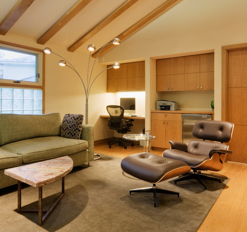 Modern furnished studio in Seattle featuring a cozy sofa, work desk, lounge chair, and compact kitchenette—ideal for short-term stays.